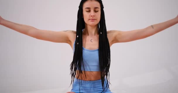 Młoda kobieta medytująca w pozycji lotosu z zamkniętymi oczami - Materiał filmowy, wideo