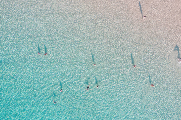 人々はターコイズブルーの海の水の空中ビューで泳ぐ。ギリシャの太陽の下で浅い水の楽しみ。晴れた夏の日、旅行先 - 写真・画像