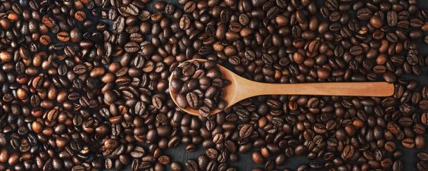 Κόκκοι καφέ υφή ή φόντο. Καφέδες καβουρδισμένοι. Κοντινό πλάνο. Οι κόκκοι καφέ μπορούν να χρησιμοποιηθούν ως φόντο. Φρέσκοι φρυγμένοι κόκκοι καφέ. κόκκοι καφέ σε ξύλινη κουτάλα - Φωτογραφία, εικόνα