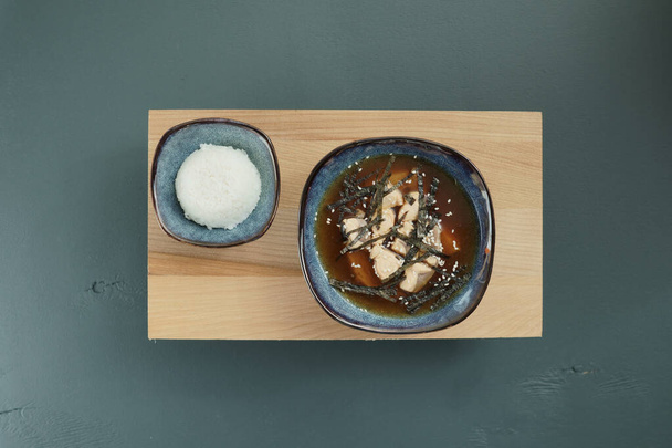 Sopa de miso japonesa y arroz en un tazón rojo y cuchara en la mesa
. - Foto, imagen