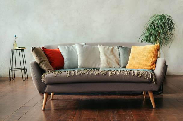 Grijze bank met kussens van verschillende kleuren in een moderne woonkamer interieur. - Foto, afbeelding