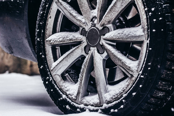 Foto de auto aro sujo e pneu de pé na estrada tempo neve. - Foto, Imagem