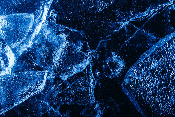 Foto de trozos de hielo agrietados congelados tonificados azules textura superficial sobre telón de fondo oscuro. - Foto, Imagen