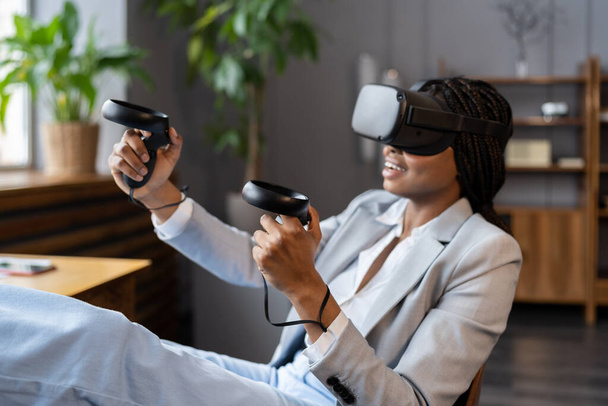 興奮アフロ女性は、 vrメガネを着用ビジネスのための仮想現実ヘッドセットのジョイスティックの経験を保持します - 写真・画像