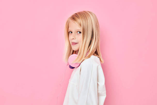 мила дівчина блондинка волосся навушники позує рожевий фон
 - Фото, зображення