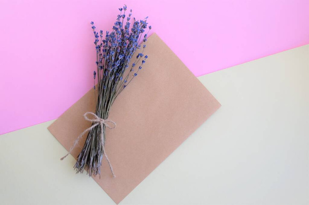 délicat bouquet de lavande sur fond jaune-rose avec une enveloppe artisanale, minimalisme - Photo, image