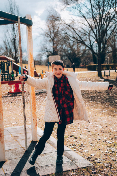 Zehnjähriges Mädchen in weißer Jacke hat Spaß auf dem Spielplatz - Foto, Bild