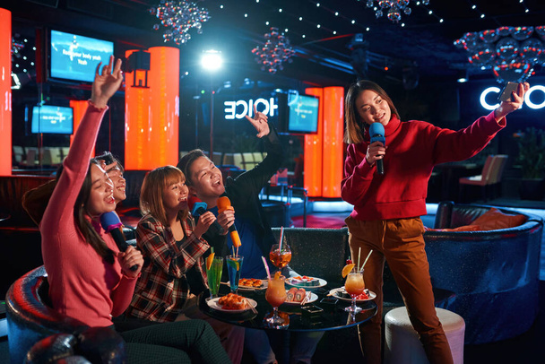 Asian group of friends singing songs at karaoke club - Fotó, kép