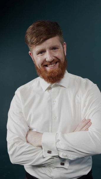 Un giovane ragazzo con i capelli rossi e la barba in posa in camicia bianca con gemelli - Foto, immagini