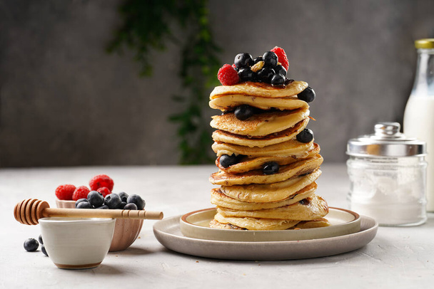Fitness blueberry pancakes with protein, raspberries and walnuts stacked on top of each other on light grey background - Photo, Image