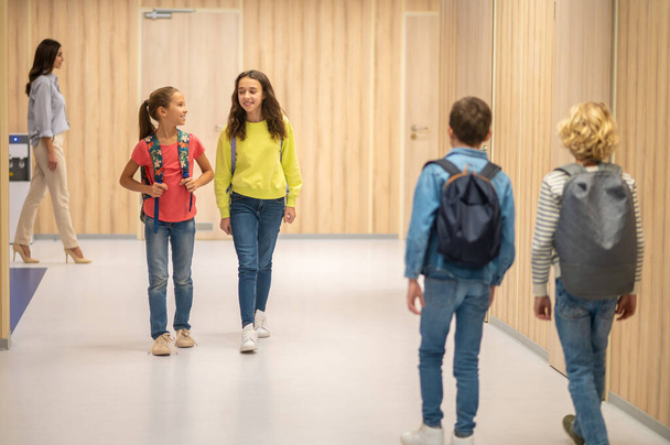 Girls walking hallway and boys with backs to camera - Foto, Bild