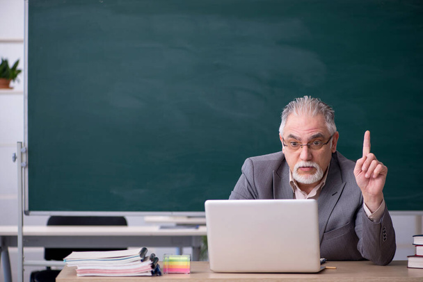 Oude mannelijke leraar voor schoolbord in telestudy concept - Foto, afbeelding