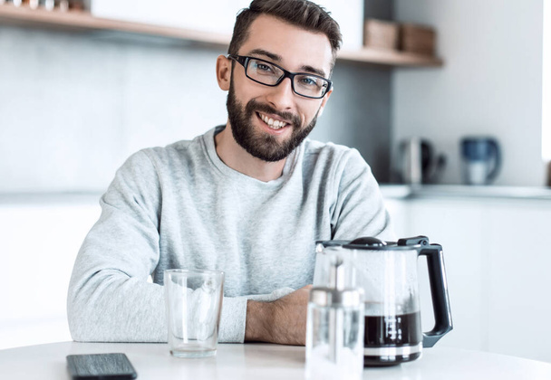 attractive man sitting at the kitchen table in the morning - Foto, imagen