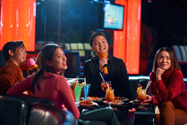Young happy asian people having fun while singing karaoke on night party at bar. - Foto, Bild