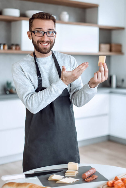 attraktiver Mann zeigt ein Stück köstlichen Käse - Foto, Bild
