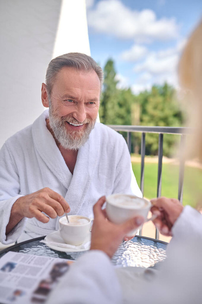 A couple in whote robes having morning coffee at the balcony - Foto, immagini