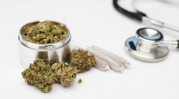 marijuana buds, grinder, joints with  phonendoscope, stethoscope, on with white background. - Фото, изображение