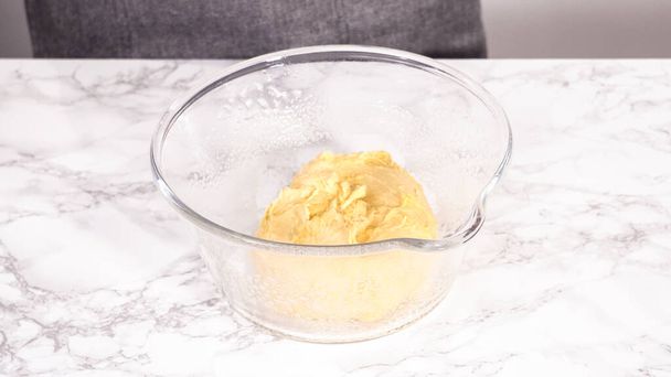 Step by step. Rising brioche dough in a glass mixing bowl on the kitchen counter. - Фото, зображення