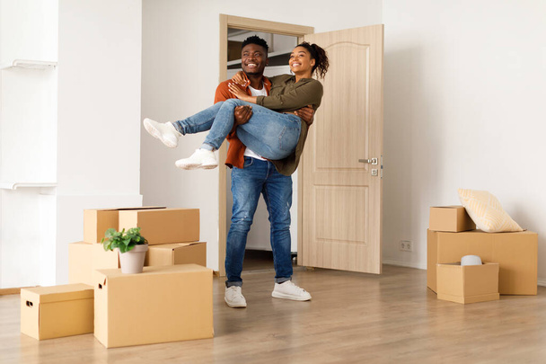 新しい家に入る腕の中で妻を運ぶ喜びの黒人夫 - 写真・画像