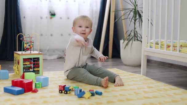 χαριτωμένο μικρό αγόρι παίζει με μπλοκ στο παιδικό δωμάτιο - Πλάνα, βίντεο