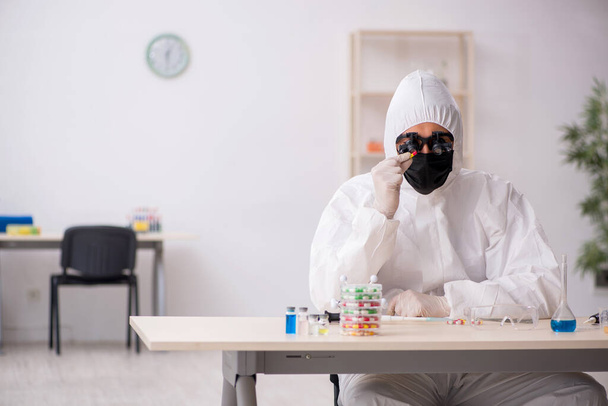 Young male chemist in drugs synthesis concept - 写真・画像