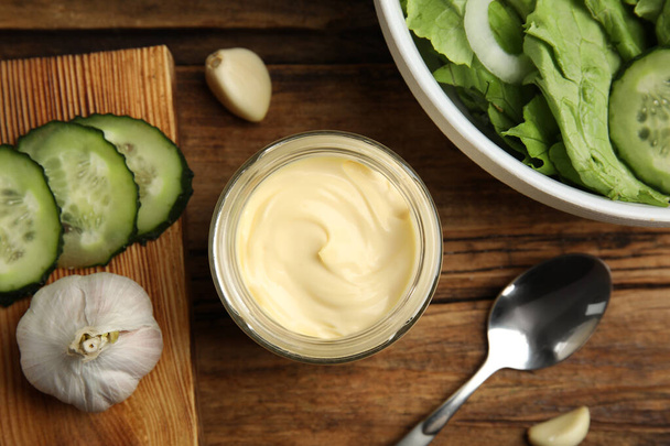 Jar of delicious mayonnaise, salad and vegetables on wooden table, flat lay - Photo, Image