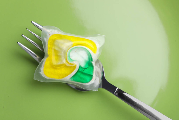 Green plate with fork and dishwasher detergent pod, top view - Photo, Image