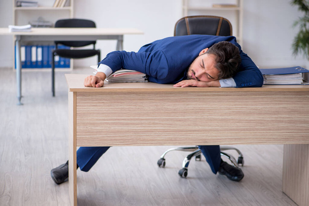 Νεαρός άνδρας υπάλληλος εξαιρετικά κουρασμένος στο γραφείο - Φωτογραφία, εικόνα