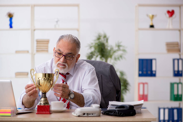 Velho empregado do sexo masculino sendo premiado com copo de ouro - Foto, Imagem
