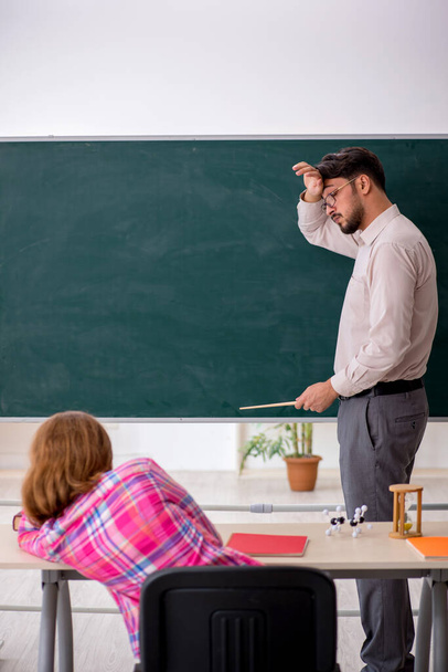 Fiatal férfi tanár és vörös hajú lány az osztályteremben - Fotó, kép