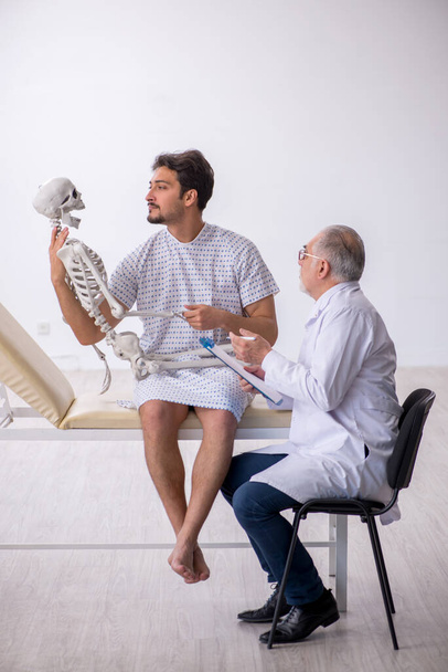 Старий лікар-психіатр вивчає молодого пацієнта-чоловіка
 - Фото, зображення