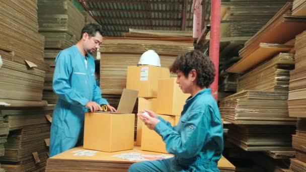 Dva bezpečnostní pracovníci a kolegové používají snímač čárových kódů pro kontrolu zásilek zásilek ve skladu balíků, továrna na výrobu papíru pro obalový průmysl, logistické přepravní služby. - Záběry, video