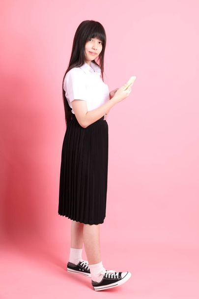 The teen Asian girl with university uniform standing on the pink background. - Zdjęcie, obraz