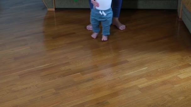 Infant barefoot baby girl boy learning to walk standing on warm floor. - Footage, Video