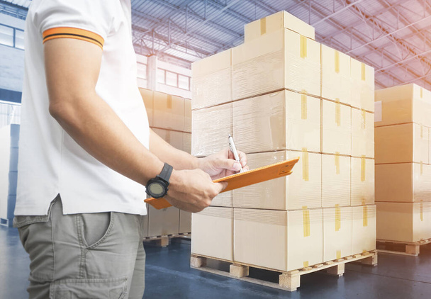 Warehouse Worker Holding Clipboard Doing Inventory Management Packaging Boxes in Storage Warehouse. Shipment Checking Stock Godds Boxes. Shipping Warehouse Logistics - Photo, Image