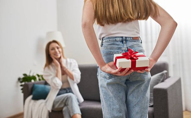 Crop daughter preparing to give surprise present to mother - Foto, Imagen