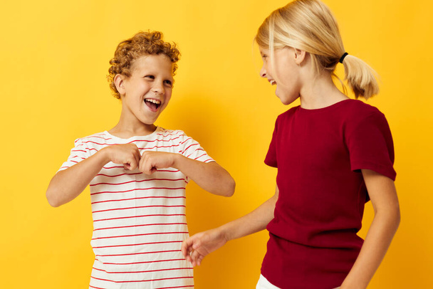 Niños pequeños de pie lado a lado posando emociones de la infancia sobre un fondo de color - Foto, imagen