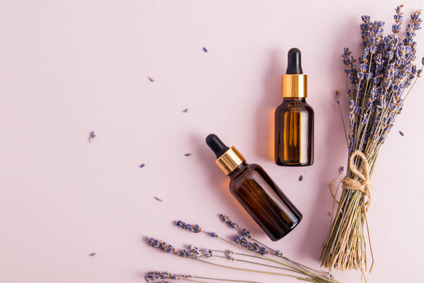 fashionable cosmetic product in glass bottles on a purple background. oil or serum lavender for face and body skin care. top view - Fotoğraf, Görsel