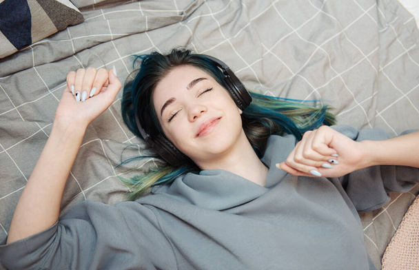 Fiatal tinédzser lány kék hajjal és fülhallgatóval  - Fotó, kép