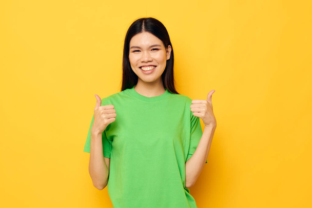 Charming young Asian woman in green t-shirts gestures with his hands emotions studio model unaltered - Fotó, kép