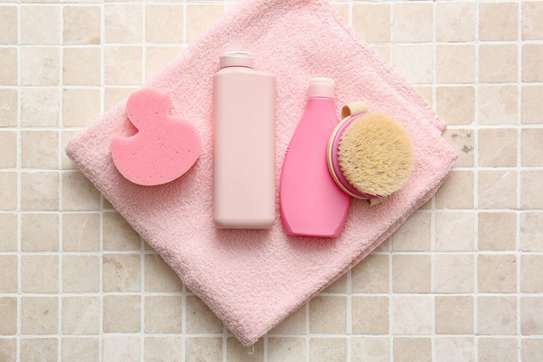 Temiz havlu, kozmetik ürünleri şişeleri, banyo süngeri ve renkli fayanslarda masaj fırçası. - Fotoğraf, Görsel