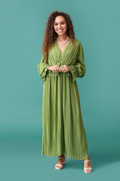 Joven mujer afroamericana en vestido con joyas con estilo sobre fondo verde - Foto, imagen