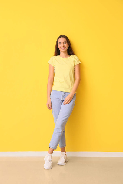 Pretty young woman in stylish t-shirt on yellow background - Foto, Bild