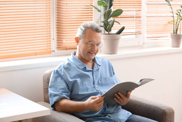 Hombre mayor en anteojos leyendo revista en casa - Foto, imagen