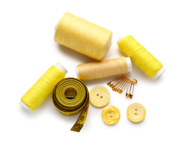 Thread spools with measuring tape, buttons and pins on white background - Photo, Image