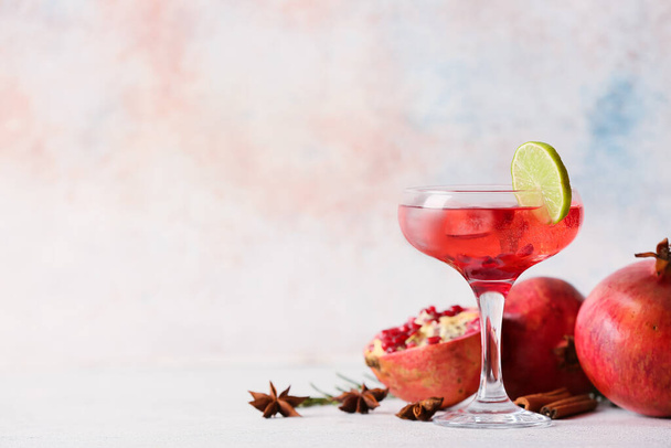 Glass of tasty pomegranate cocktail on light background - Fotó, kép