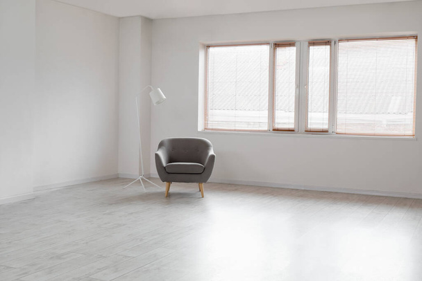 Moderne fauteuil en standaard lamp in de buurt van raam in lege kamer - Foto, afbeelding