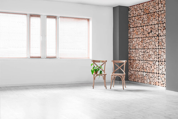 Дерев'яні стільці з кімнатним рослиною у великій порожній кімнаті
 - Фото, зображення