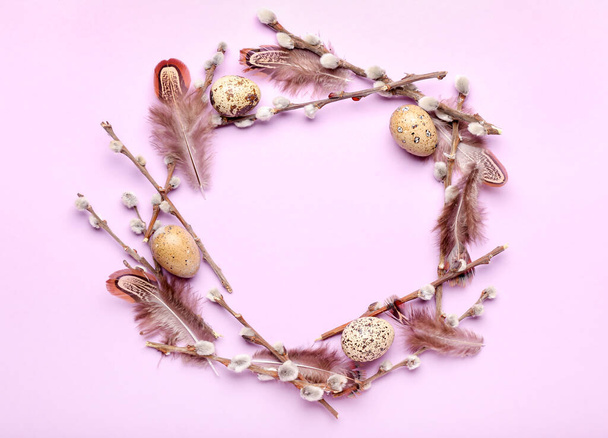 Stylish wreath with Easter eggs, willow branches and feathers on purple background - Photo, Image