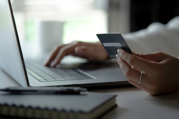 Kredi kartı tutan ve dizüstü bilgisayar kullanan bir kadın. İnternetten alışveriş - Fotoğraf, Görsel